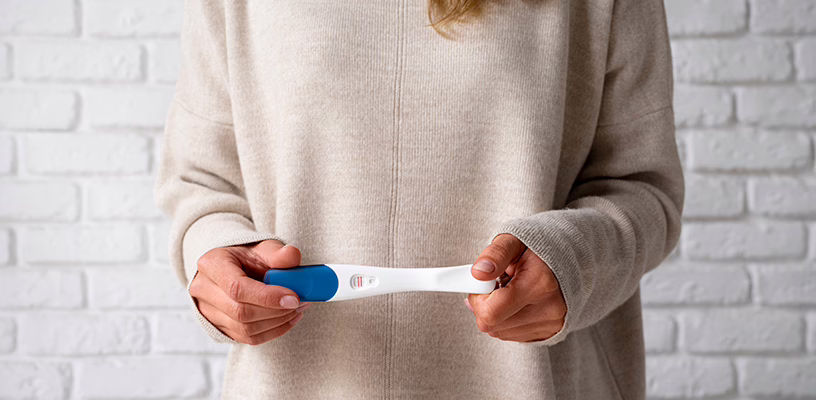Woman holding a false-positive pregnancy test in her hands.
