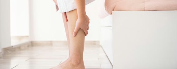 Pregnant woman holding her leg in a clinic, checking for varicose veins.