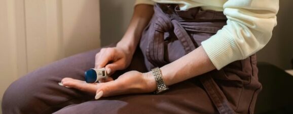 A woman holding a pregnancy test, unsure when she should take it as her periods are irregular.