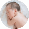 One-month-old baby sleeping on his side with his head resting on his arm.