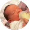 One week old baby drinking milk from baby bottle with his eyes closed.