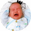 Fussy two-month-old baby lying in crib, crying, and raising arms.
