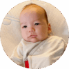 Swaddled three-month-old baby propped up against pillow.