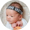 Three-week-old baby lying on pillow and looking sideways while playing with his fingers.