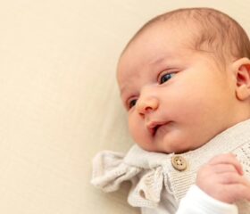 A 3-week-old baby lying on her back and looking to the left.