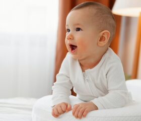 A 5-month-old baby sitting up and laughing.