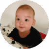 Smiling five-month-old baby pushing himself up on pillows.