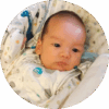 Five-week-old baby lying in bassinet and looking sideways.