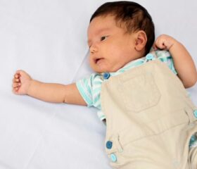 A 5-week-old baby lying on his back and giggling.
