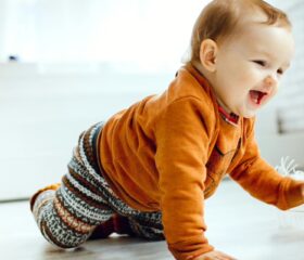 A 6-month-old baby crawling and laughing.