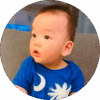 Seven-month-old baby sitting up in couch and looking around.
