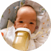 Seven-week-old baby propped up against pillow while drinking from bottle.