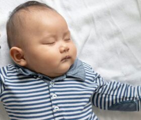 An 8-week-old (2-month-old) baby lying on his back and sleeping.