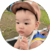 9-month-old baby sitting outside in park and wearing hat to protect from sun.