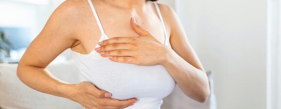 A newly pregnant woman massaging her right breast as she's dealing with breast tenderness.