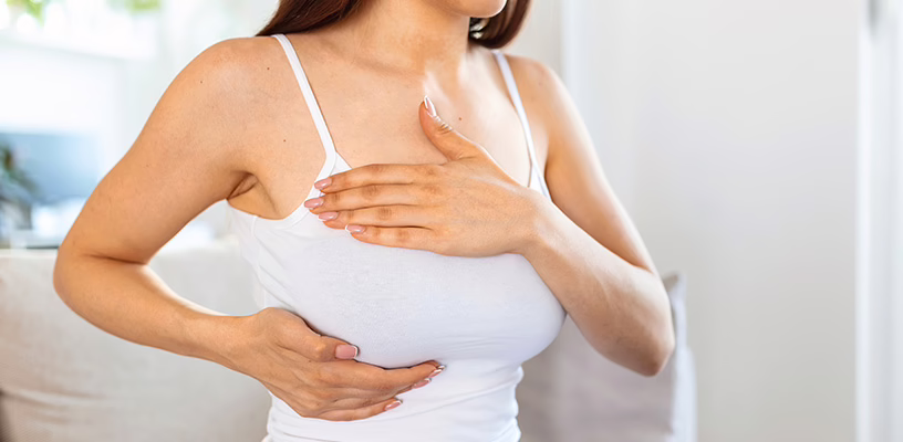 A newly pregnant woman massaging her right breast as she's dealing with breast tenderness.