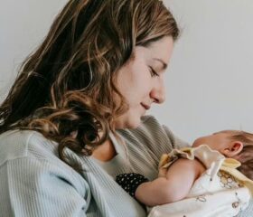 Woman holding her baby to her chest as she looks for signs of cradle cap.