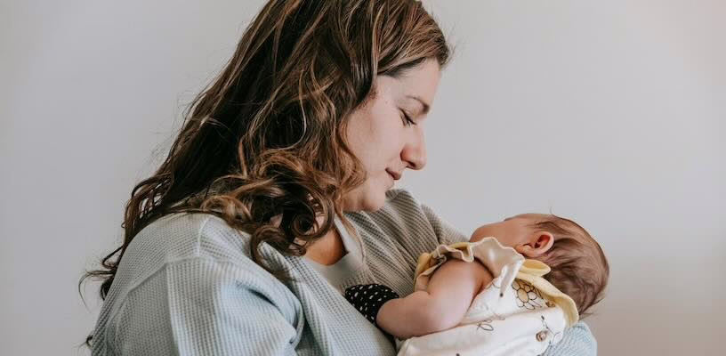Woman holding her baby to her chest as she looks for signs of cradle cap.