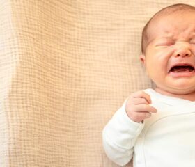 Young baby lying down and crying.
