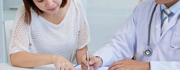 A woman and her doctor reviewing a document that goes over the costs of freezing and storing her eggs.