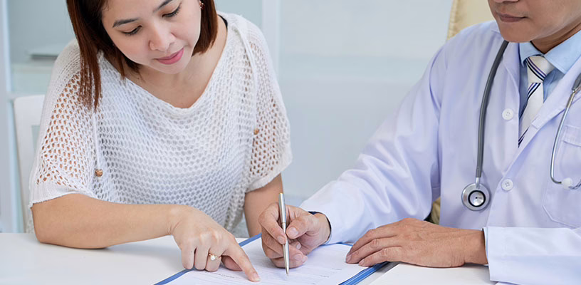 A woman and her doctor reviewing a document that goes over the costs of freezing and storing her eggs.