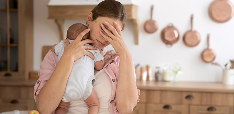 A new mother carrying her baby, while feeling overwhelmed as a result of postpartum depression.