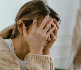 Woman holding her head in her hands as she struggles to calm her postpartum rage.