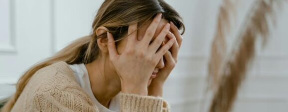 Woman holding her head in her hands as she struggles to calm her postpartum rage.