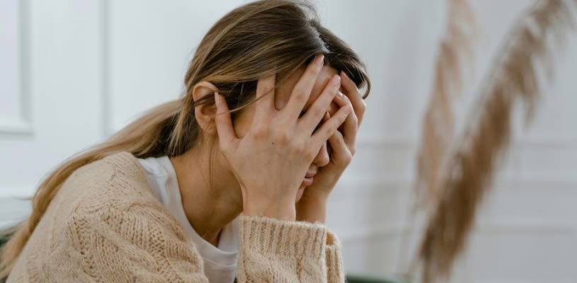 Woman holding her head in her hands as she struggles to calm her postpartum rage.