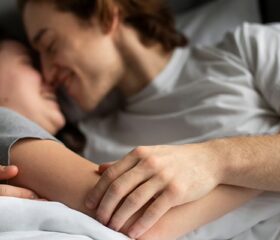 Couple snuggling together in bed.