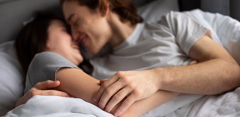 Couple snuggling together in bed.