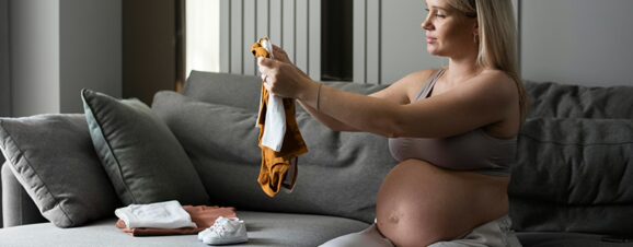 A pregnant women who's entered her third trimester organizing her baby's clothes.
