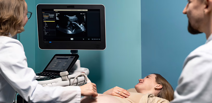 Woman in a doctor's office looking at her baby's first ultrasound.