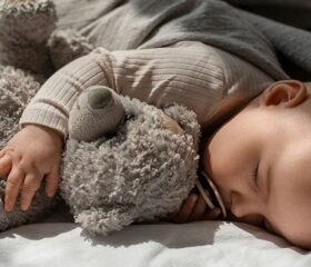 Baby sleeping quietly while hugging a teddy bear.