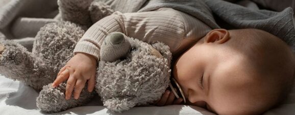 Baby sleeping quietly while hugging a teddy bear.