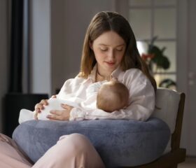 Mother holding her newborn baby while looking at one of his moles.