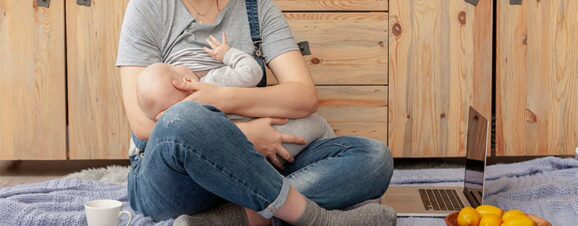 Woman sitting cross-legged on the floor while breastfeeding.