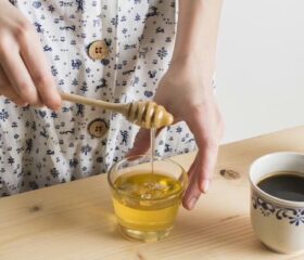 Pregnant women using a honey dipper to add honey to her drink.