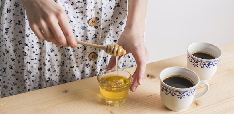 Pregnant women using a honey dipper to add honey to her drink.