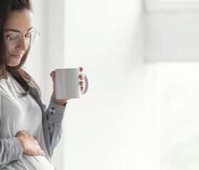 Smiling pregnant woman holding a cup of coffee.