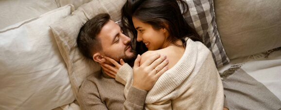 A man and a woman intimately lying on a bed as they want to try getting conceiving.