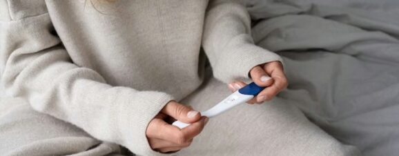 Woman looking at a positive result on an ovulation predictor kit.