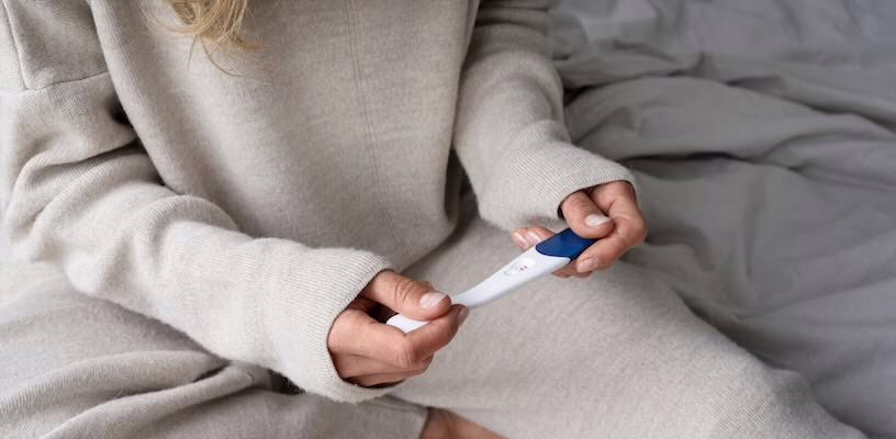 Woman looking at a positive result on an ovulation predictor kit.