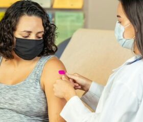 Woman getting Tdap shot in doctor's office.