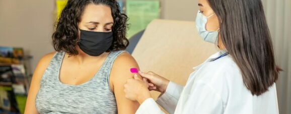 Woman getting Tdap shot in doctor's office.