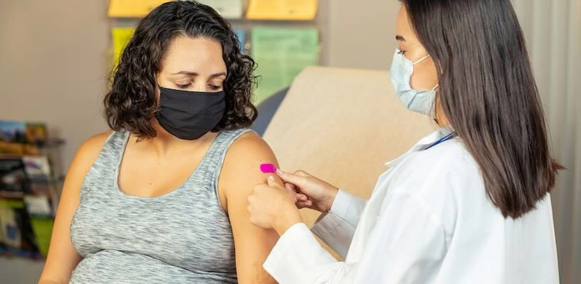 Woman getting Tdap shot in doctor's office.