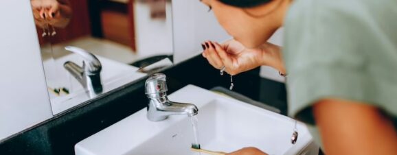 Pregnant woman brushing her teeth in front of a mirror.