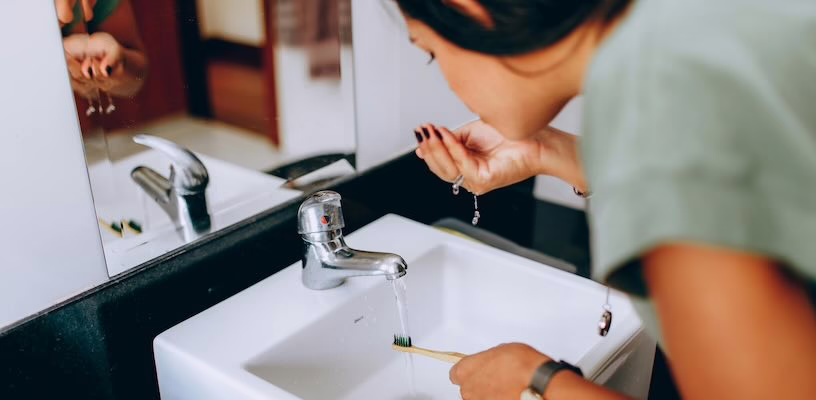 Pregnant woman brushing her teeth in front of a mirror.