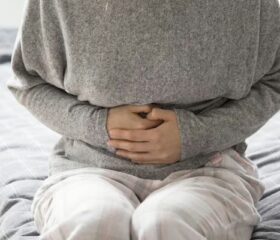 Woman clutching her stomach as she suffers from ovulation bloating.