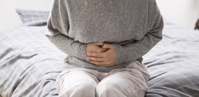 Woman clutching her stomach as she suffers from ovulation bloating.